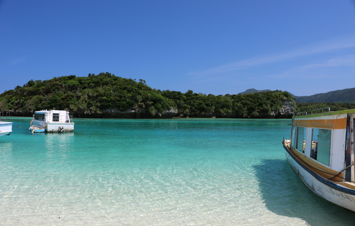 透明な海と青空が広がる静かなビーチに停泊するボート